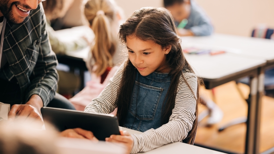 A teacher helping a student using an iPad.