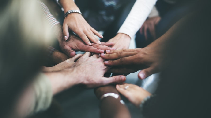 A team of people huddling and putting their hands together.