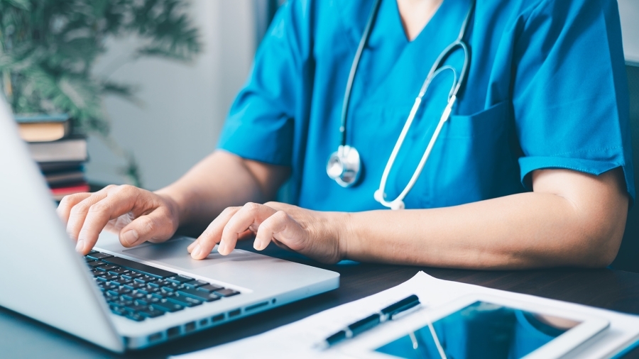 A nurse typing on a laptop.
