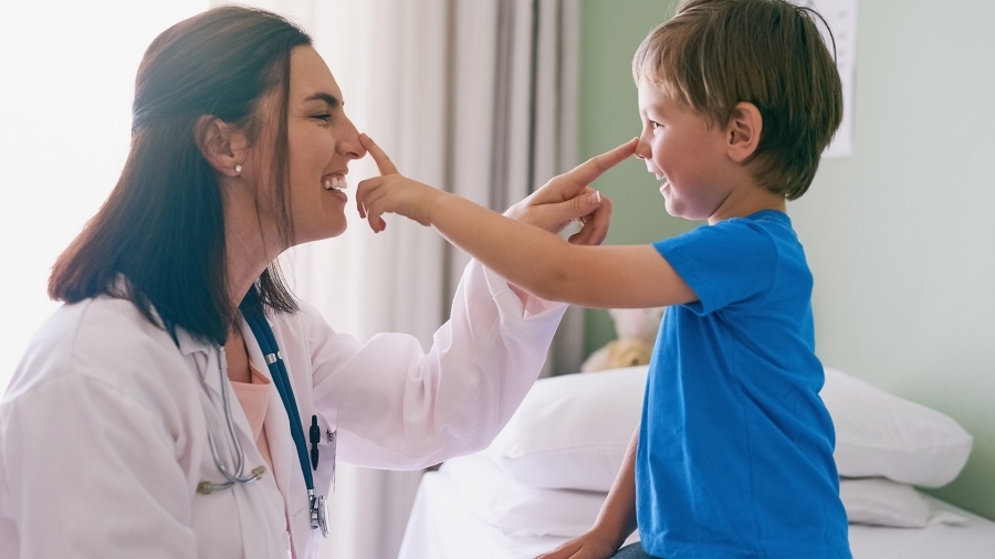 A doctor and a young patient playfully touch each other's noses.