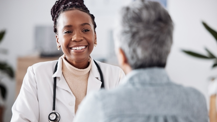 Infirmière qui regarde un patient en souriant.