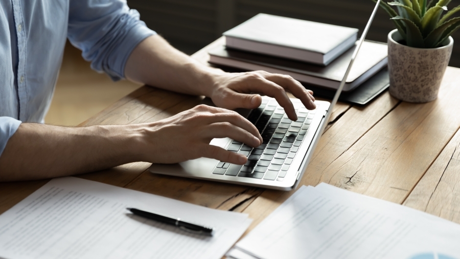 Hands typing on a laptop keyboard.