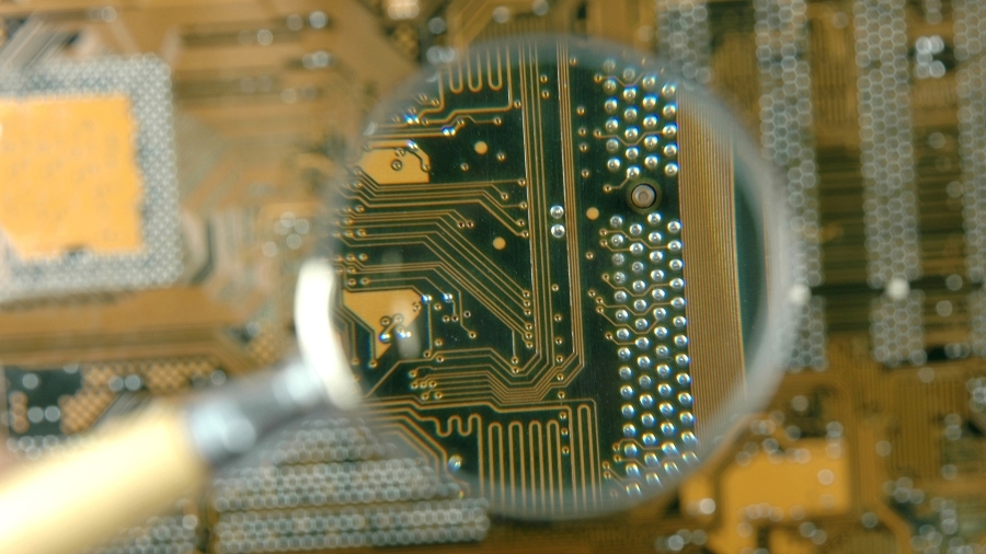 A photo of a magnifying glass being held over a circuit board.