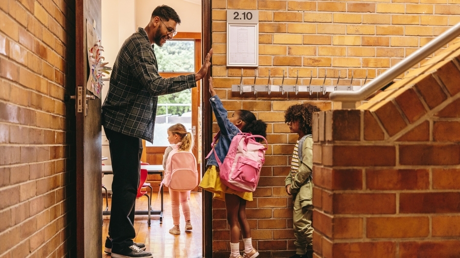 A teacher high-fives students on the way into the classroom.